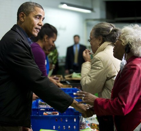 Ông Obama nắm tay trò chuyện với một người dân. Buổi phân phát thực phẩm còn có sự góp mặt của mẹ vợ tổng thống. Ảnh: AFP